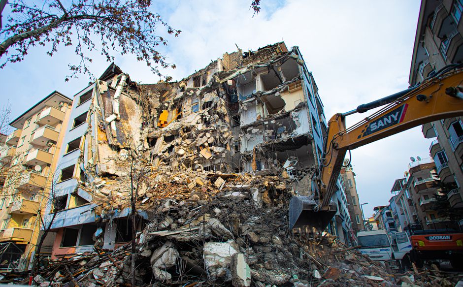 A partial demolition of a damaged building with heavy machinery.