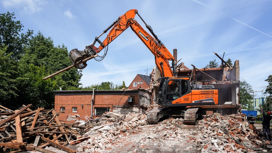 Excavator in action demolishing a brick building.